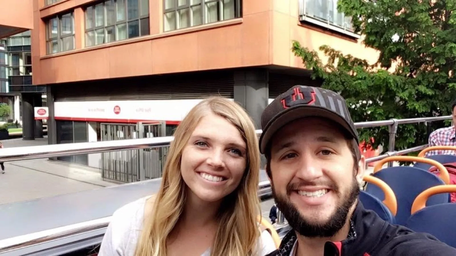 Michael and Chantelle smiling from the top deck of an open-air London tour bus