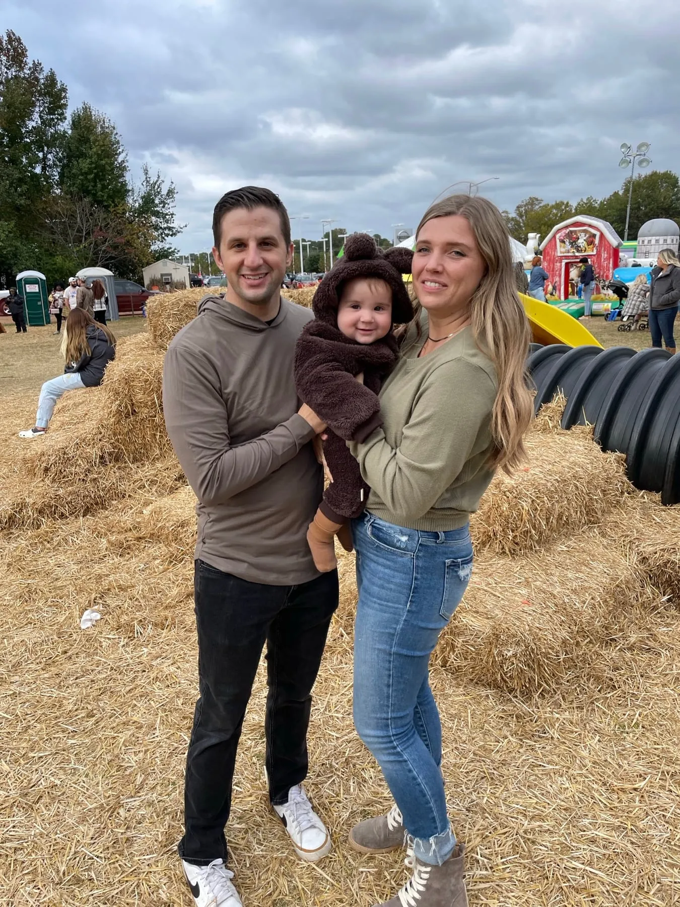 Our family holding the baby in front of hay bales at a fall festival