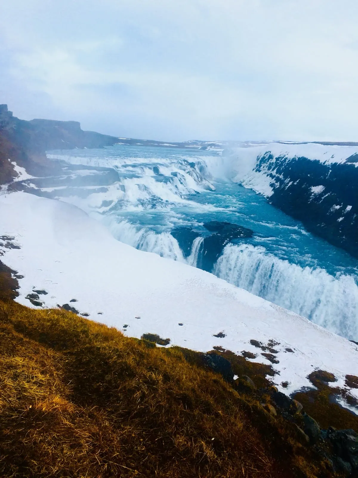 Gullfoss waterfall rushing down into a canyon edged with snow and ice