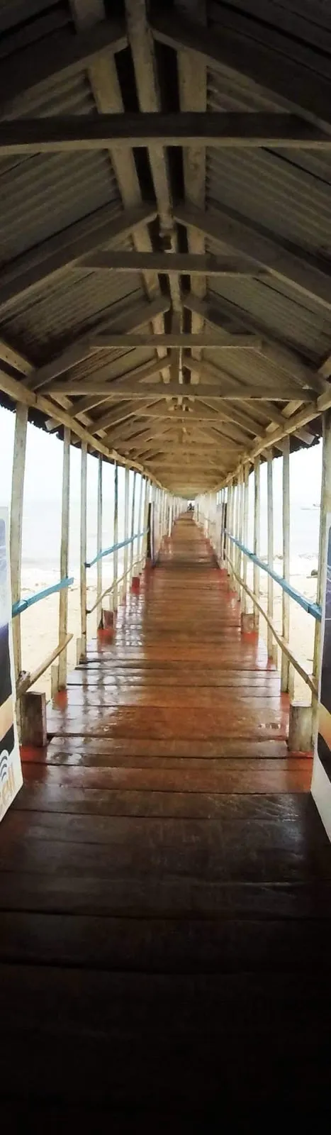 A long, covered wooden walkway leading out over the water at Lake Bosomtwe