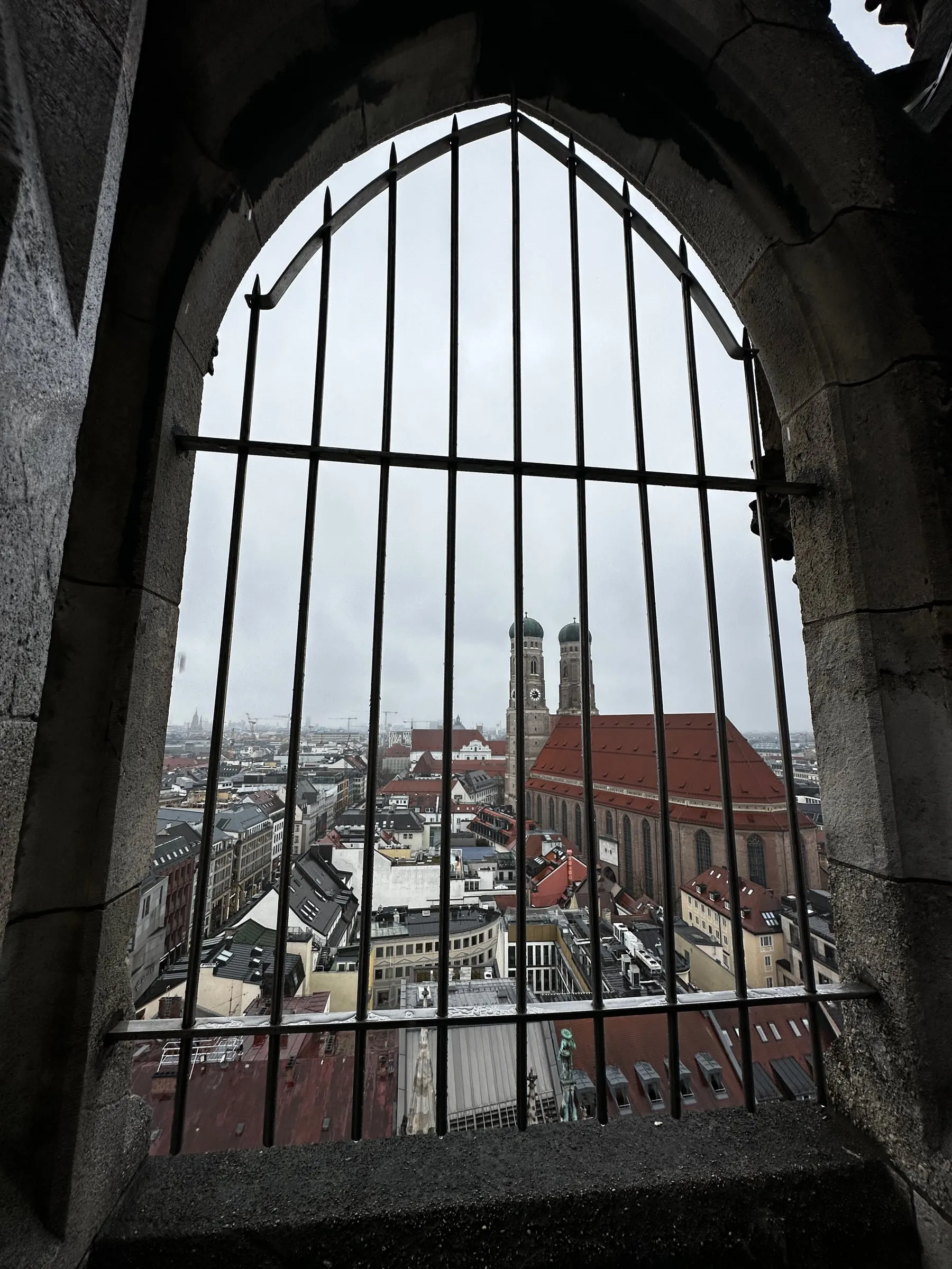 Looking out over Munich's rooftops and the twin towers of the Frauenkirche through the bars of a tower window