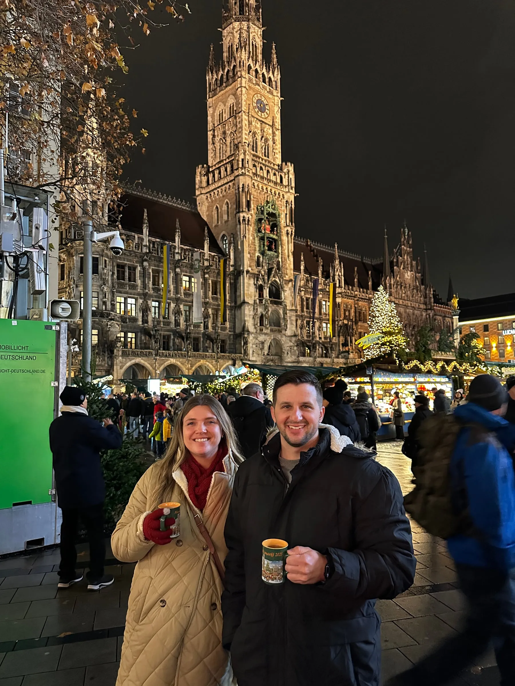 Michael and Chantelle holding glühwein mugs at the Munich Christmas market in front of the New Town Hall