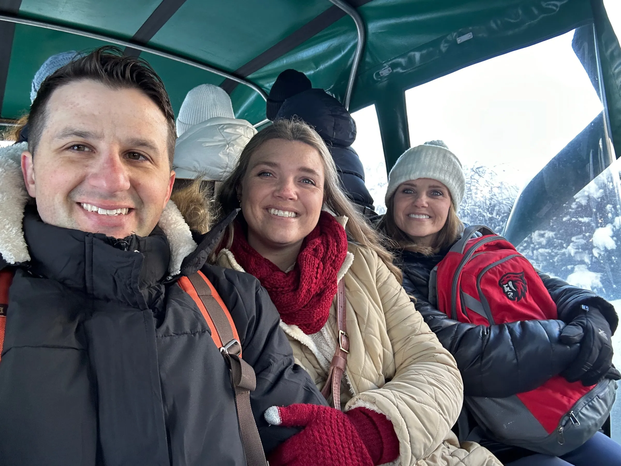 Michael and Chantelle in winter coats, scarves and gloves riding a carriage in the snow