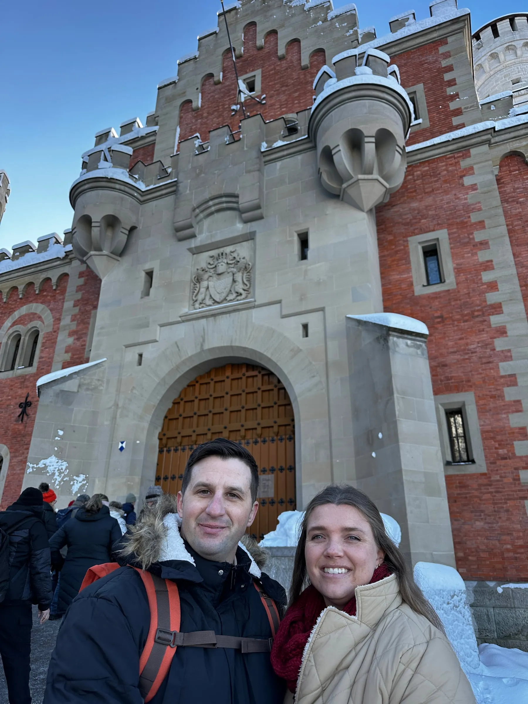 Michael and Chantelle in front of the gatehouse entrance to Neuschwanstein Castle with snow on the walls