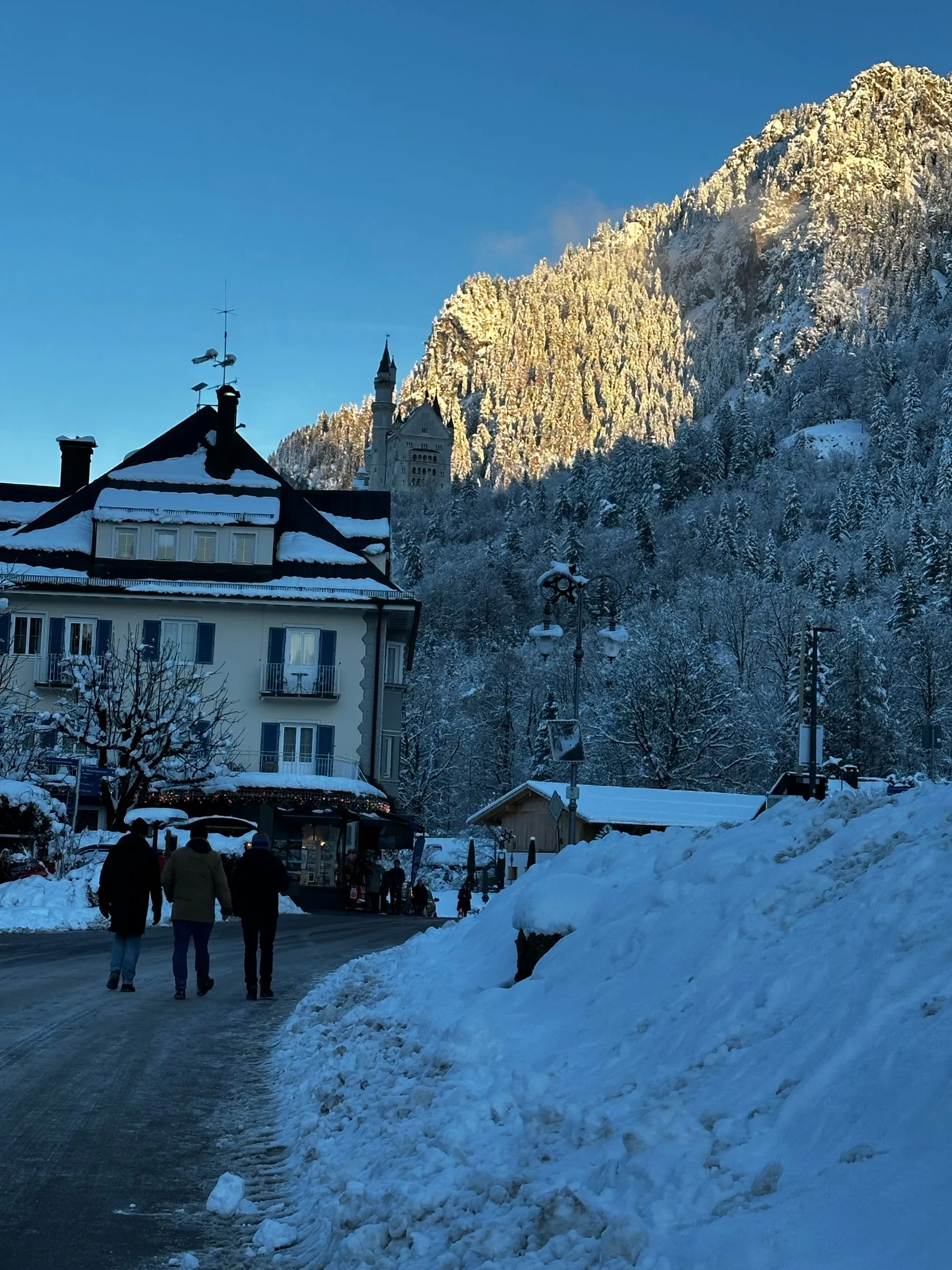 Snow-covered Hohenschwangau village with a castle on the hill in the late afternoon sun