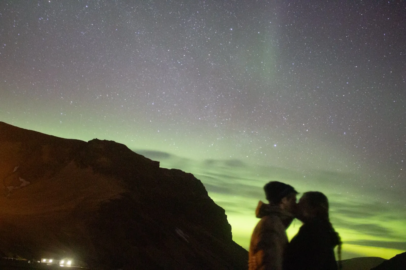 Michael and Chantelle silhouetted against green northern lights and a starry sky in Iceland