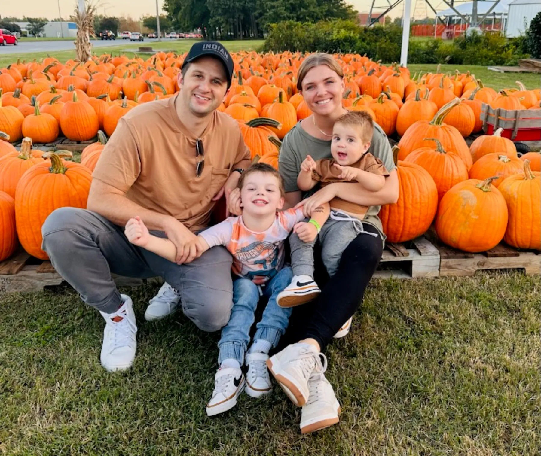 Mom, Dad and the boys sitting in front of a wall of orange pumpkins at a Virginia pumpkin patch