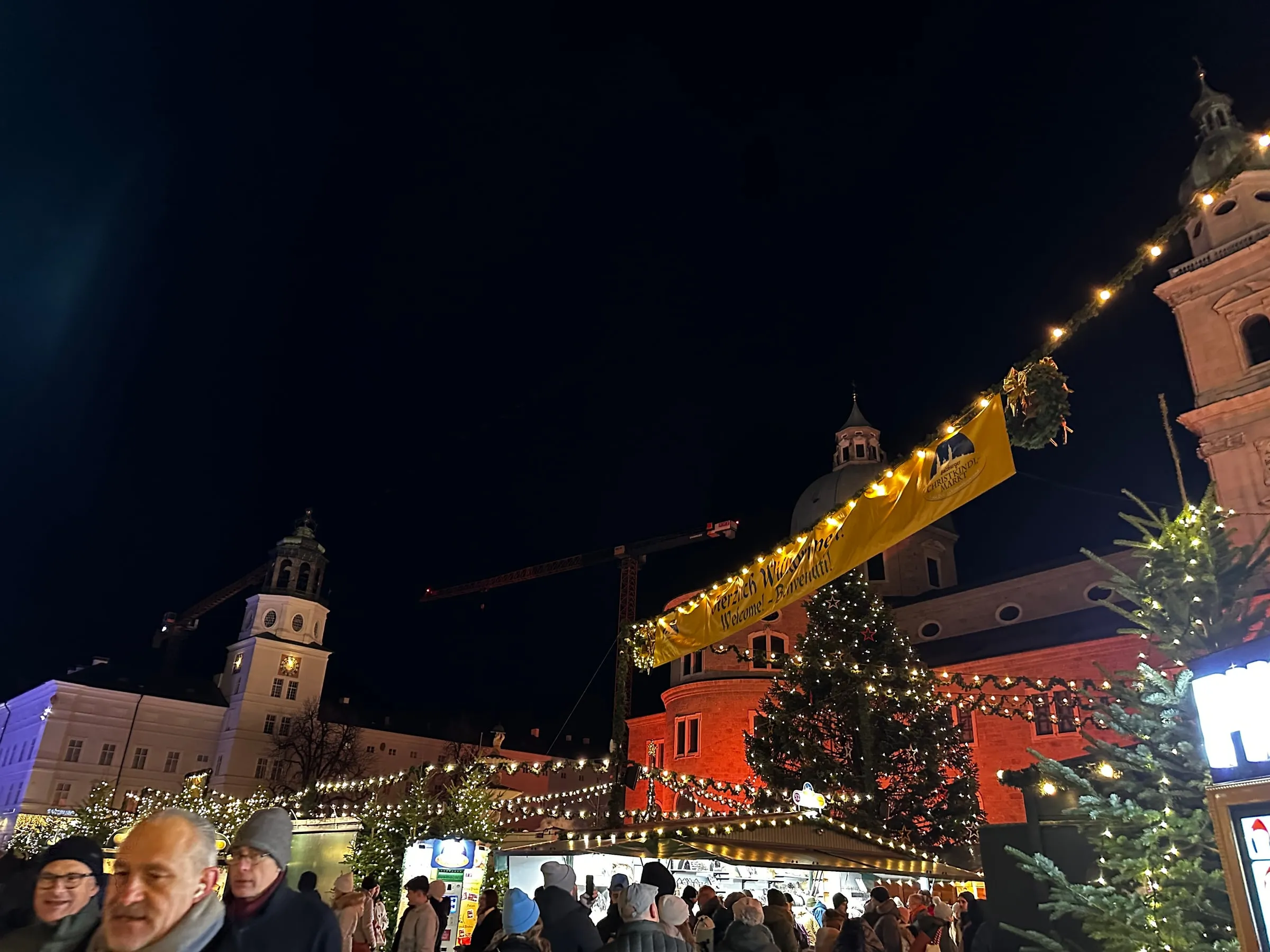 The Salzburg Christmas market at night, with a lit tree and stalls in front of the cathedral