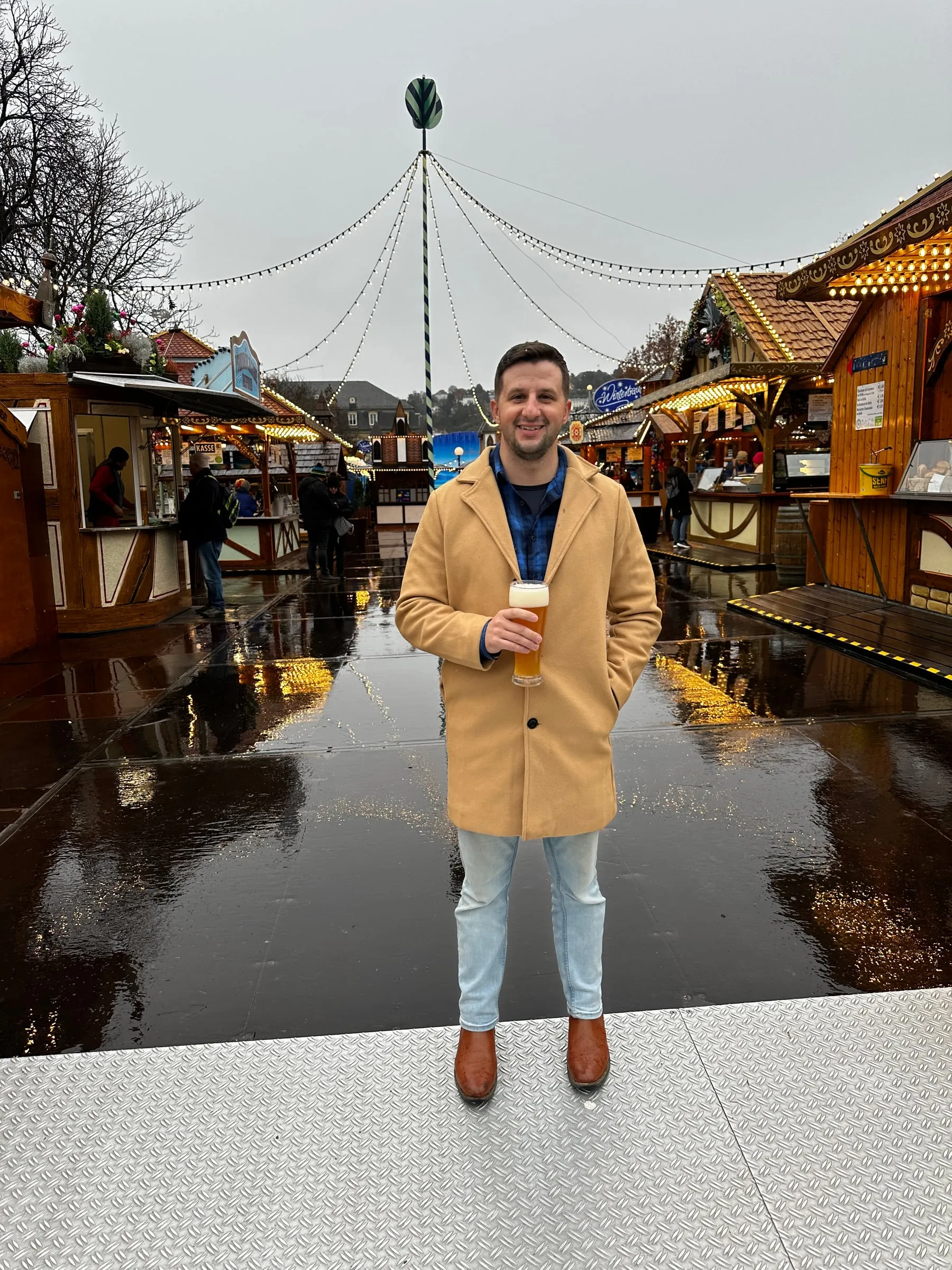 Michael standing in the middle of the Stuttgart Christmas market lined with wooden stalls