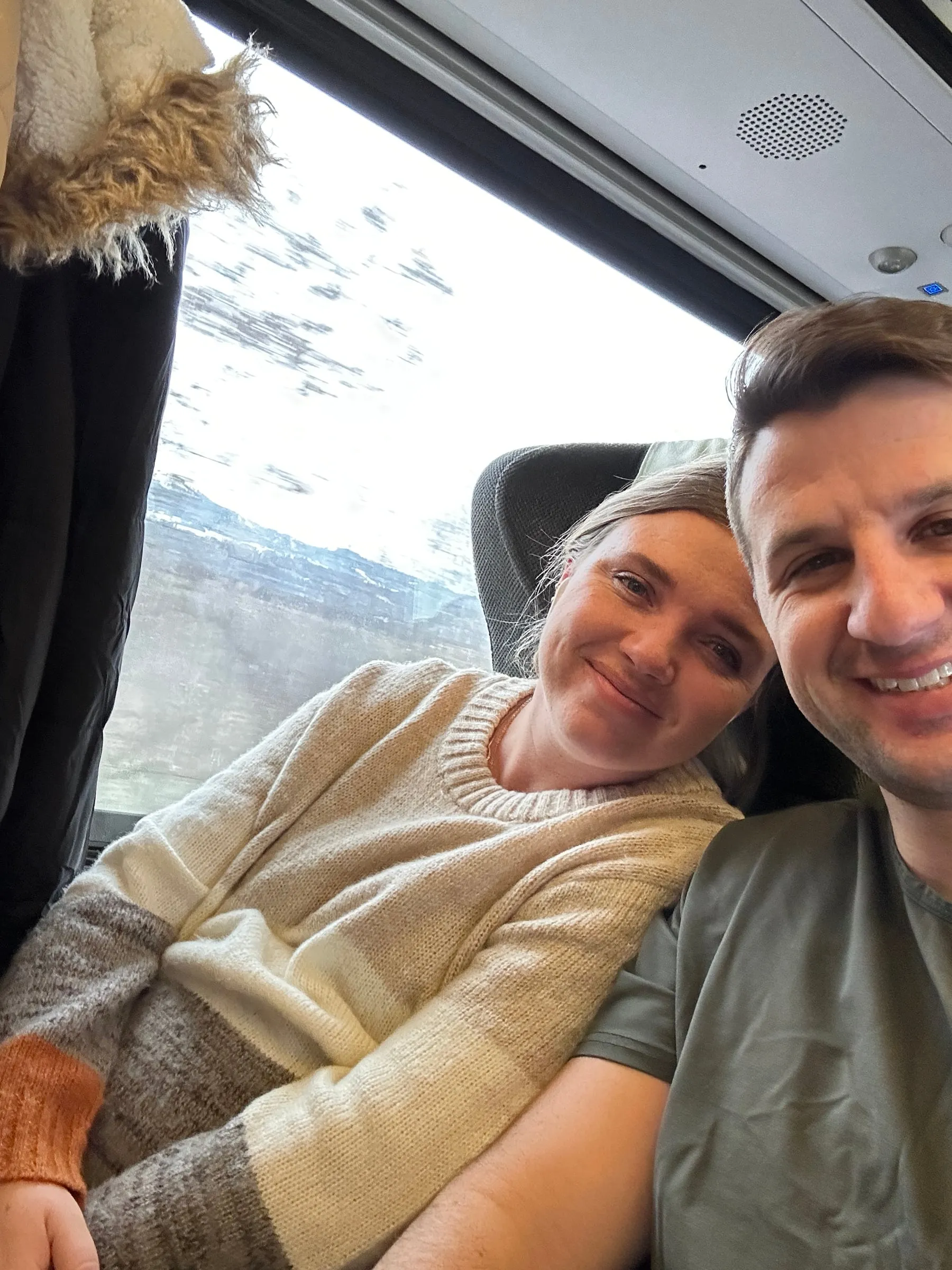 Michael and Chantelle leaning together in their train seats with mountains out the window